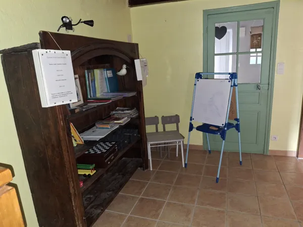 L'espace enfant avec 2 petites chaises, une table, un tableau à dessiner, des livres et des jeux