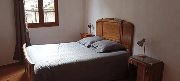 Chambre lumineuse avec lit double en bois et tables de chevet, idéale pour un séjour confortable