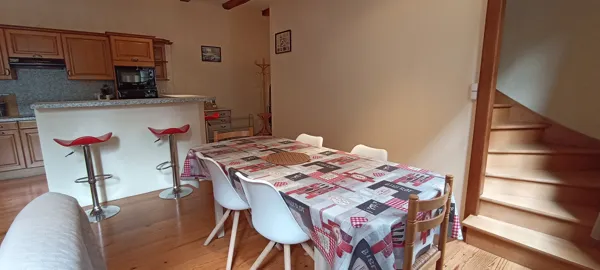 Salle à manger conviviale avec grande table familiale et accès direct à la cuisine ouverte