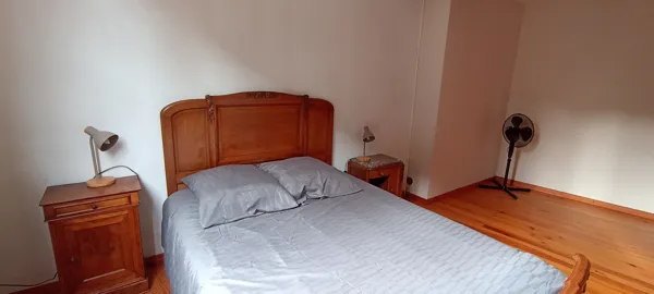 Chambre spacieuse avec lit double, tables de chevet et ventilateur pour plus de confort.