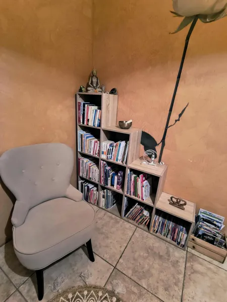 Coin lecture cosy avec fauteuil et bibliothèque, parfait pour un moment de calme et de détente à Saisonnée., Maison d’hôtes Saisonnée