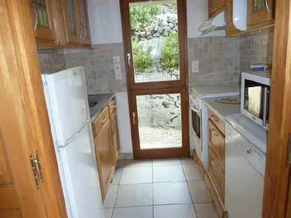 La cuisine avec cuisinière, frigidaire et freezer, lave-vaisselle et micro-ondes. La porte donne sur une courette, Domaine de Bellevue - Alain Prieur