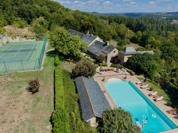 Vue d’ensemble de Les Gardes à Najac, avec la maison, la grande piscine et le court de tennis au cœur de la campagne.